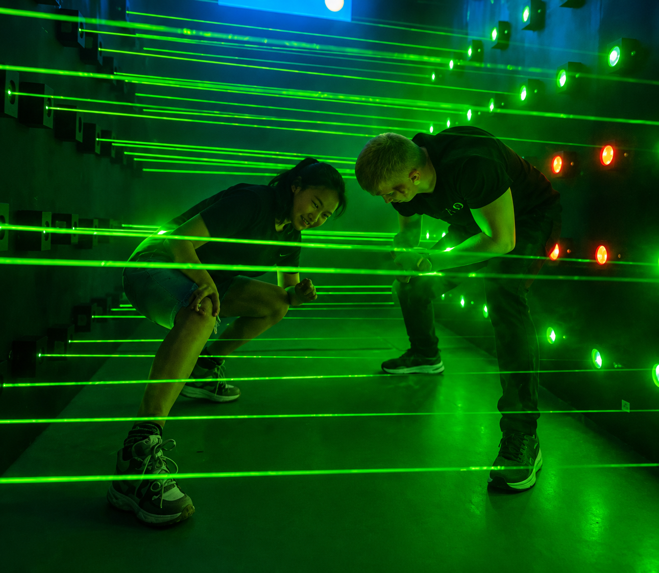 Jugadores moviéndose entre rayos láser verdes en la sala Laser.